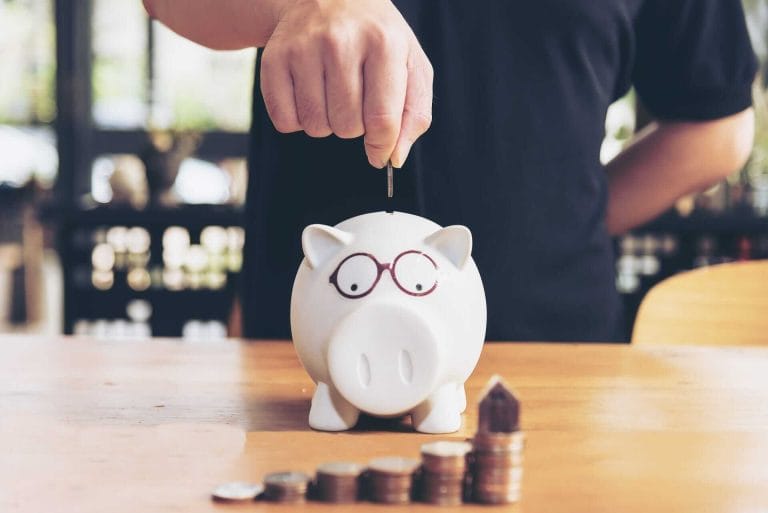 hand putting coin in piggy bank