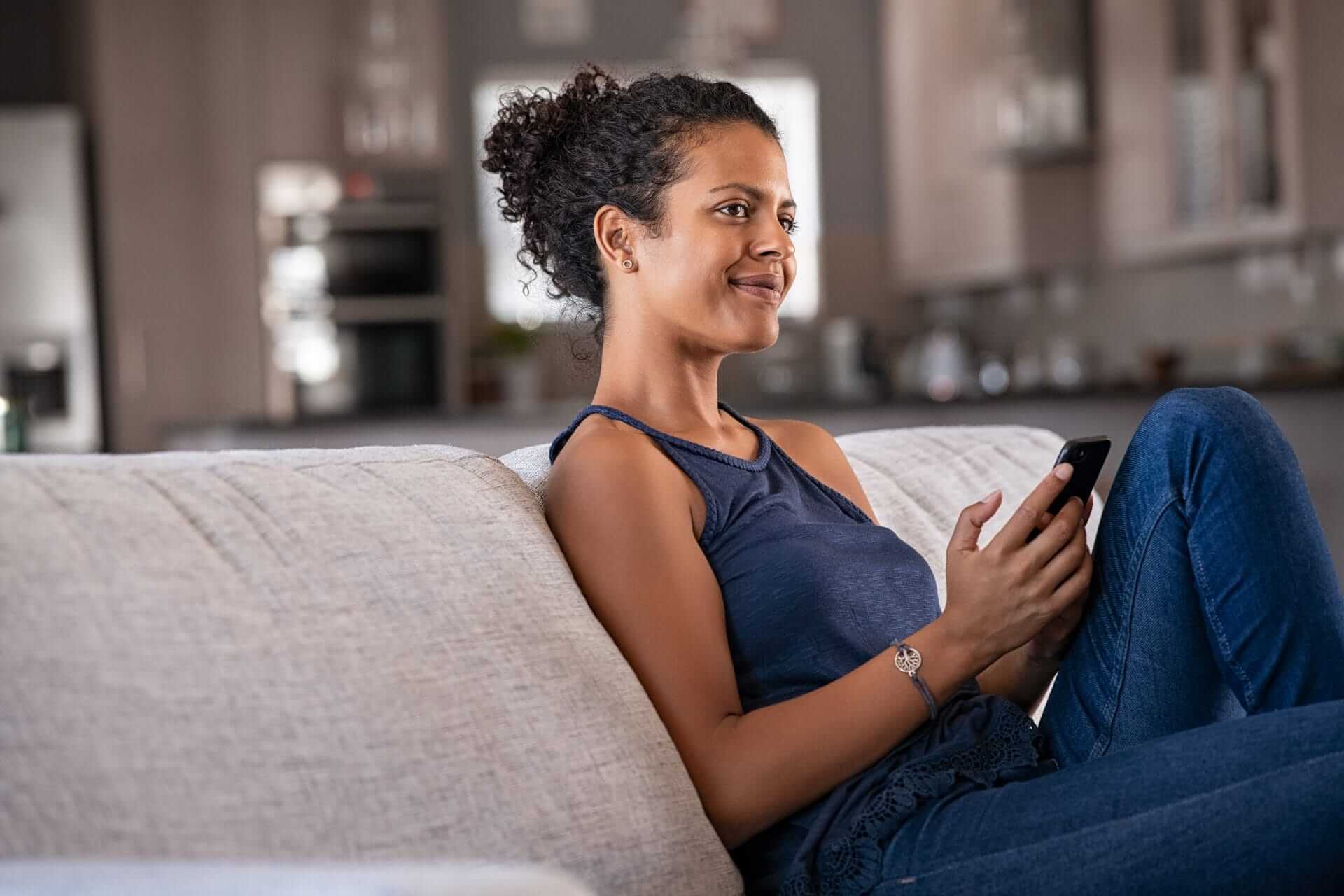 pensive young woman sitting on the couch at home